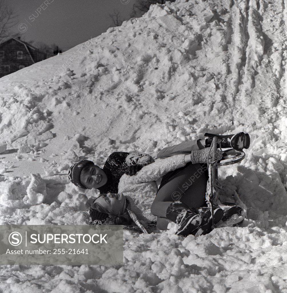 Stock Photo: 255-21641 Boy and girl lying on snow after falling down with sled
