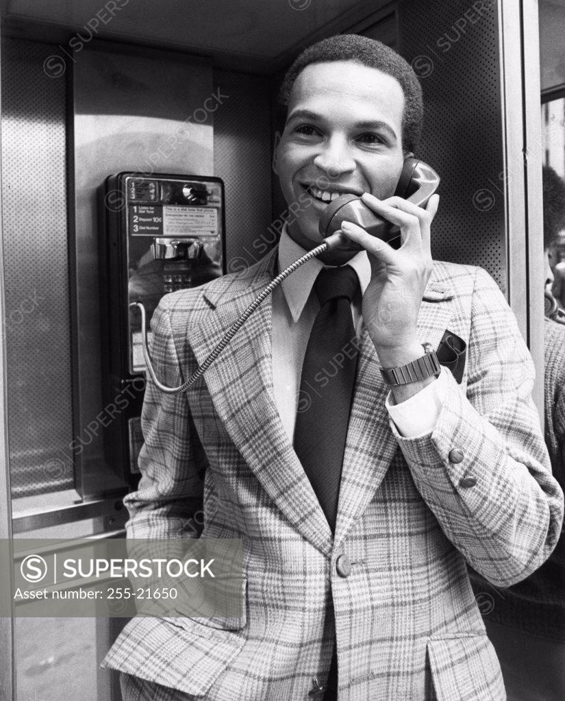 Stock Photo: 255-21650 Young man wearing suit talking in telephone booth