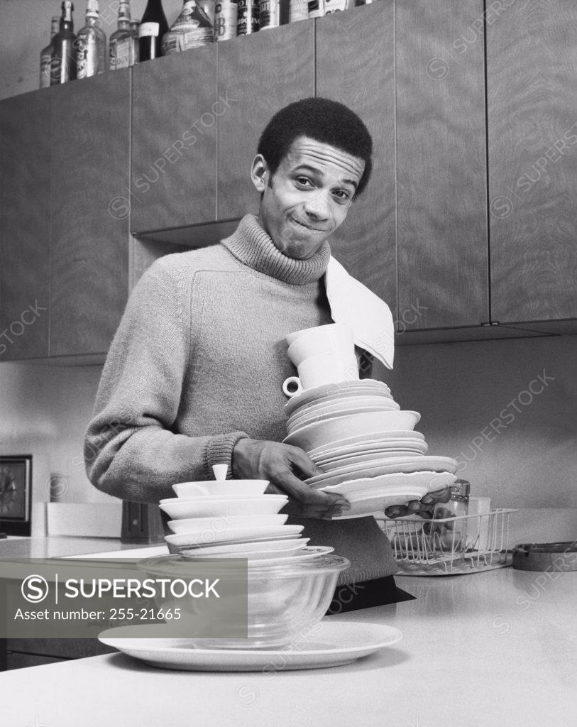 Stock Photo: 255-21665 Portrait of a young man holding dishes