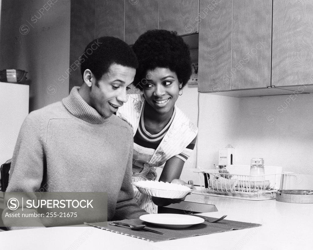 Stock Photo: 255-21675 Young woman serving food to a young man
