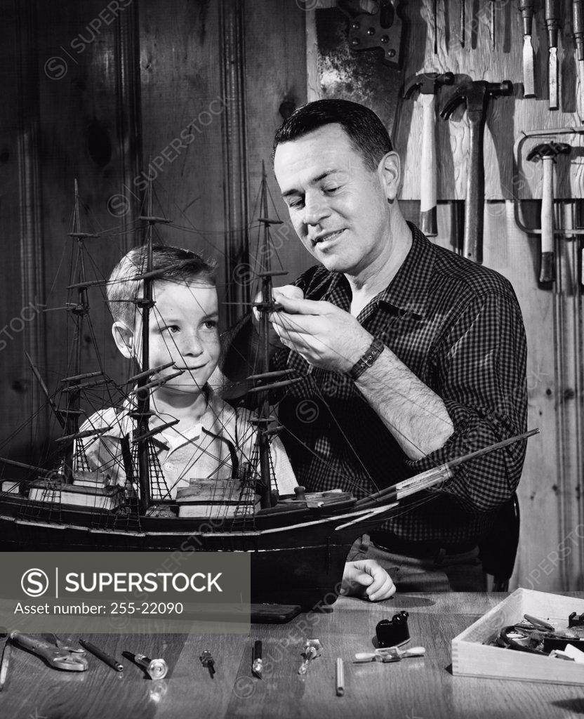 Stock Photo: 255-22090 Close-up of a mature man with his son making a model of a sailing ship