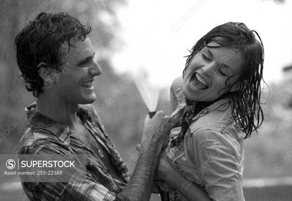 Stock Photo: 255-22388 Young couple playing with garden hose