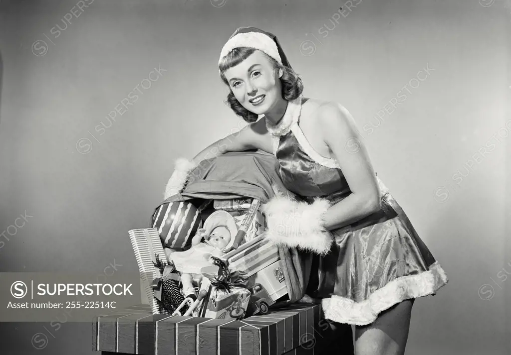 Portrait of a young woman dressed as santa dumping toys down chimney