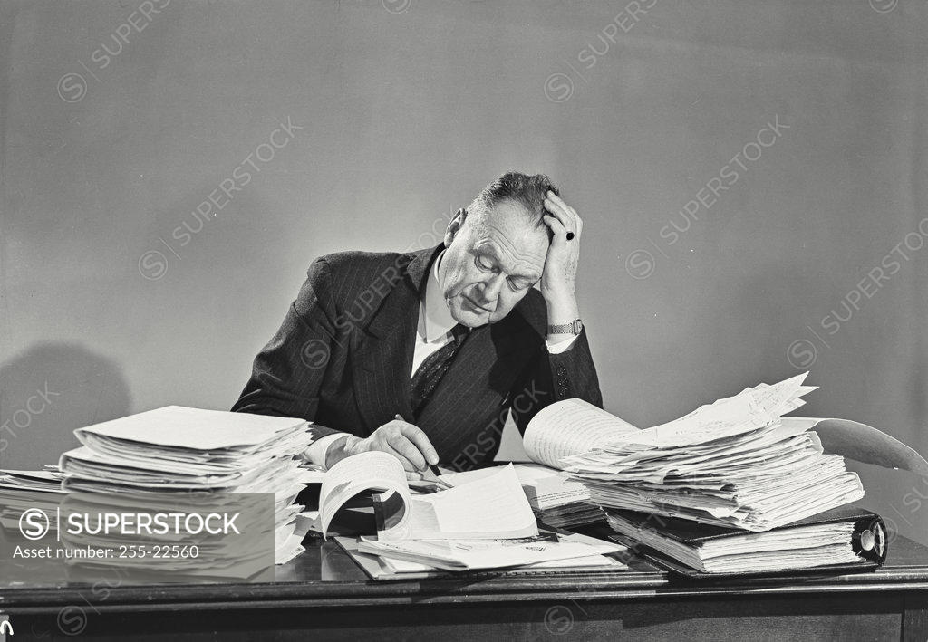 Stock Photo: 255-22560 Businessman doing paperwork with his hand on his head