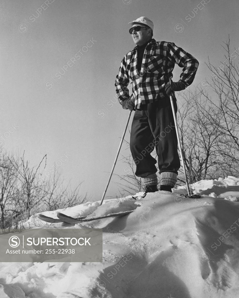 Stock Photo: 255-22938 Low angle view of a mature man holding ski poles and standing on snow