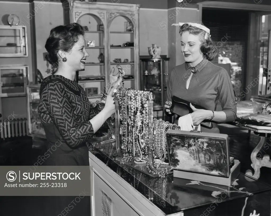 Side profile of a female sales clerk showing jewelry to a customer