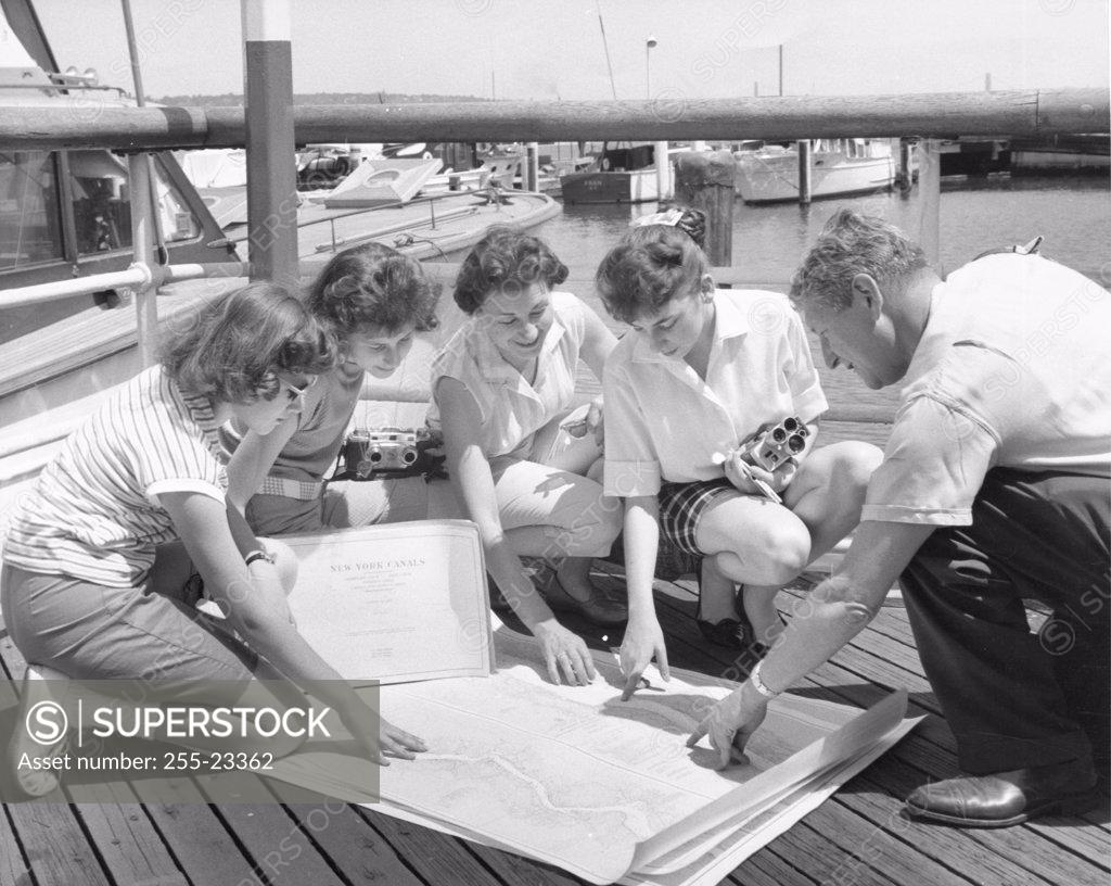 Stock Photo: 255-23362 Parents and their children looking at a map on a pier