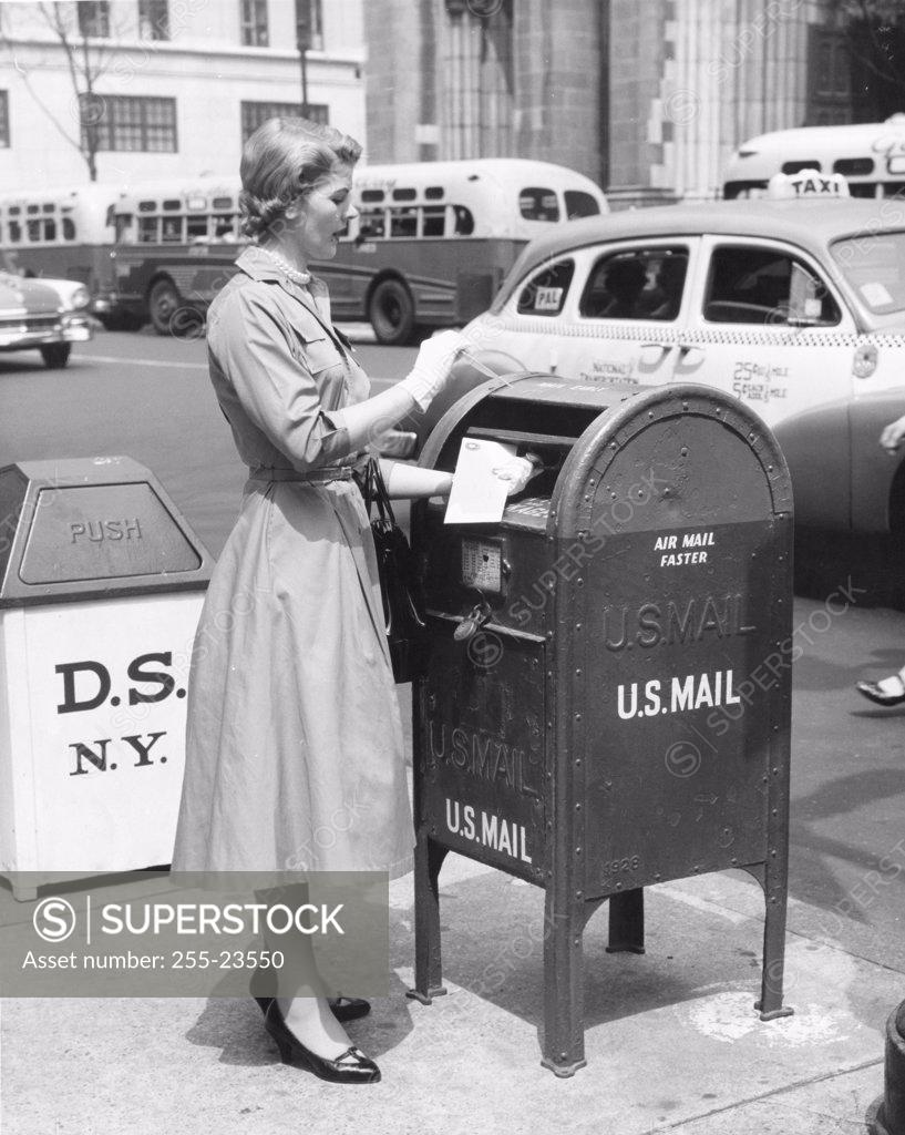 Stock Photo: 255-23550 Side profile of a mid adult woman dropping mail in a mailbox