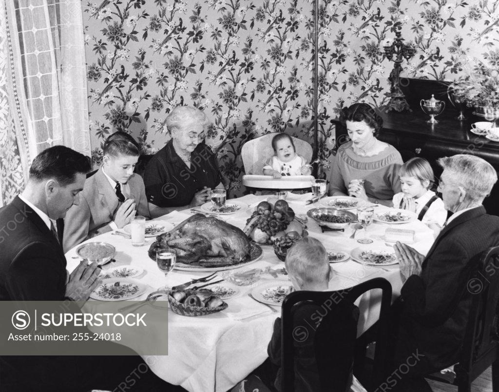Stock Photo: 255-24018 Family praying at dining table on Thanksgiving Day