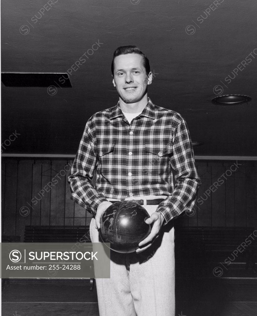 Stock Photo: 255-24288 Young adult man holding a bowling ball
