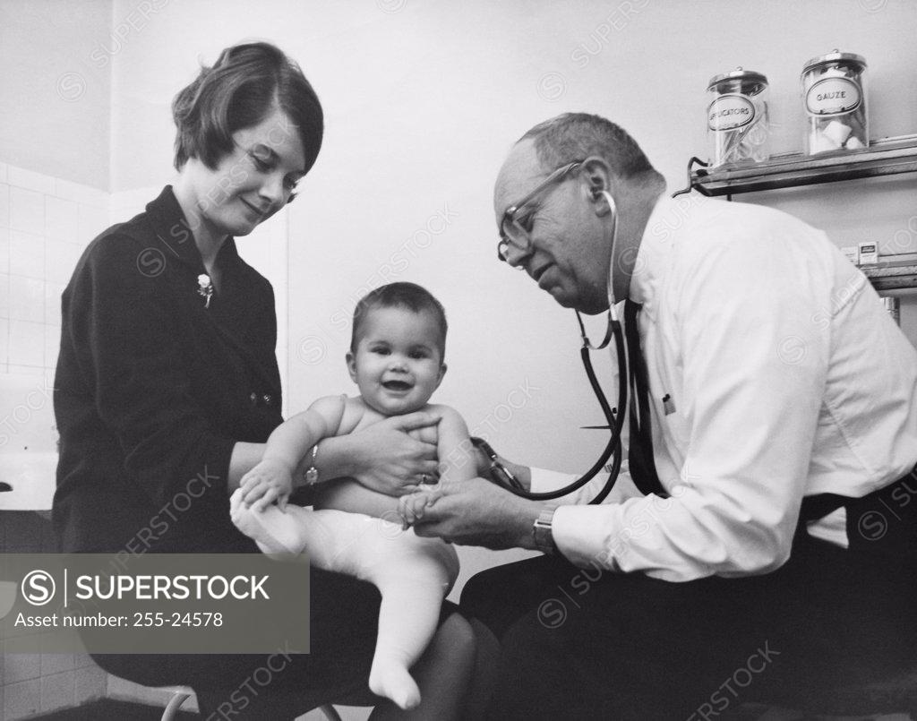 Stock Photo: 255-24578 Side profile of a male doctor examining a baby boy