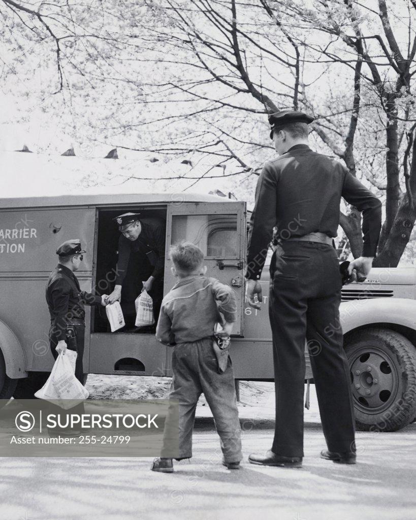 Stock Photo: 255-24799 Rear view of a boy imitating a security guard and standing near an armored truck