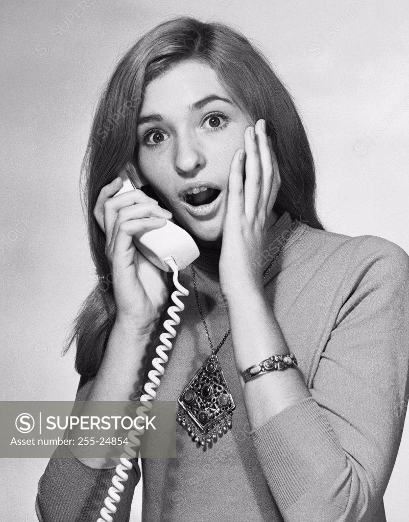 Stock Photo: 255-24854 Portrait of a young woman talking on the telephone and looking surprised