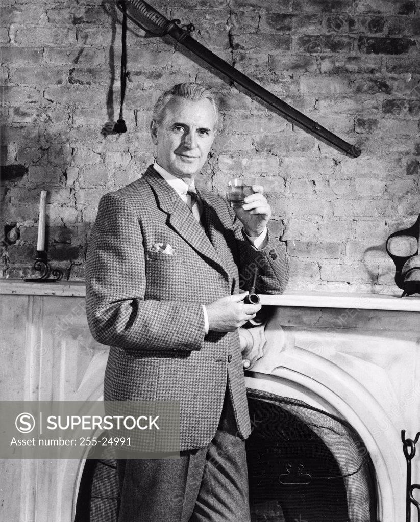 Stock Photo: 255-24991 Portrait of a mature man holding a glass of wine and a pipe