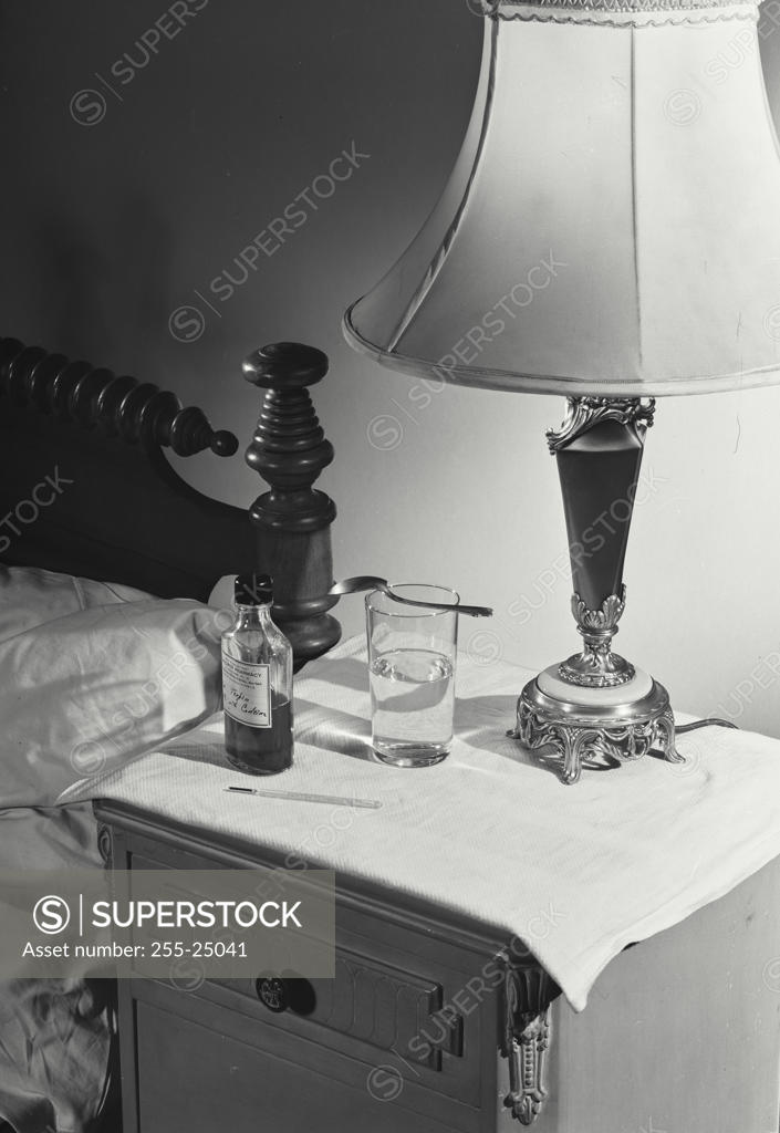 Stock Photo: 255-25041 Close-up of a medicine bottle and glass on a side table