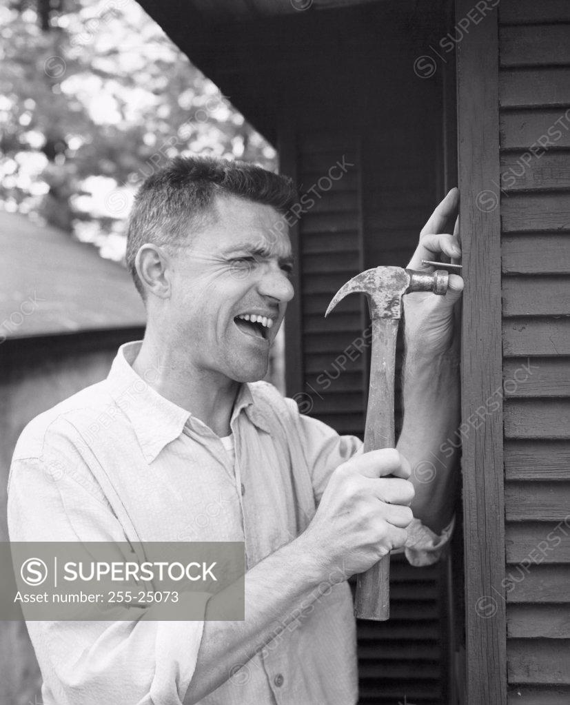 Stock Photo: 255-25073 Close-up of a mid adult man hitting his thumb with a hammer