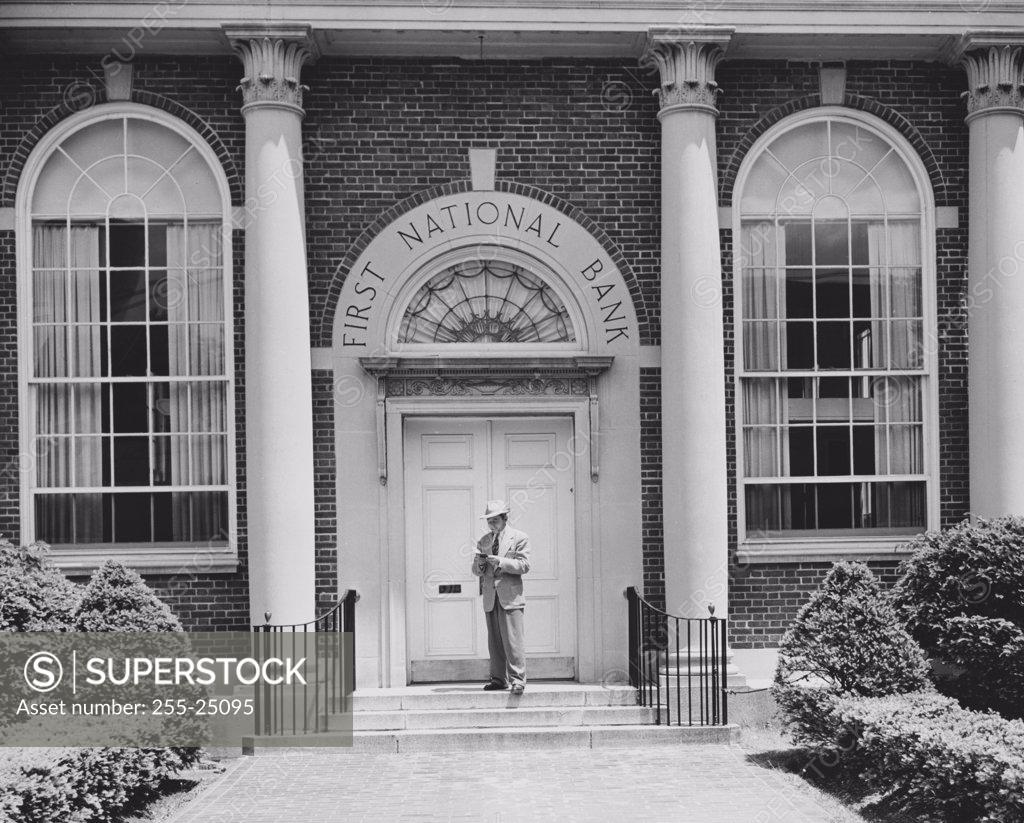 Stock Photo: 255-25095 Man standing in front of the door of a bank