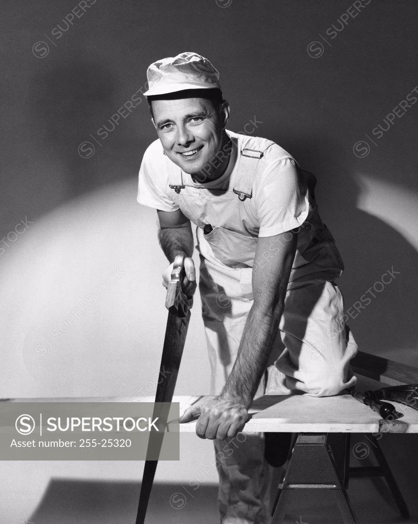 Stock Photo: 255-25320 Portrait of a carpenter sawing a wooden plank