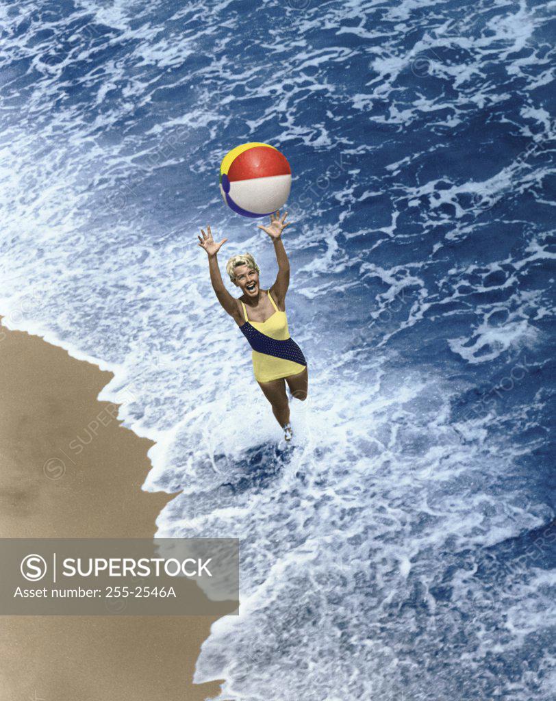Stock Photo: 255-2546A High angle view of a young woman playing with a beach ball on the beach