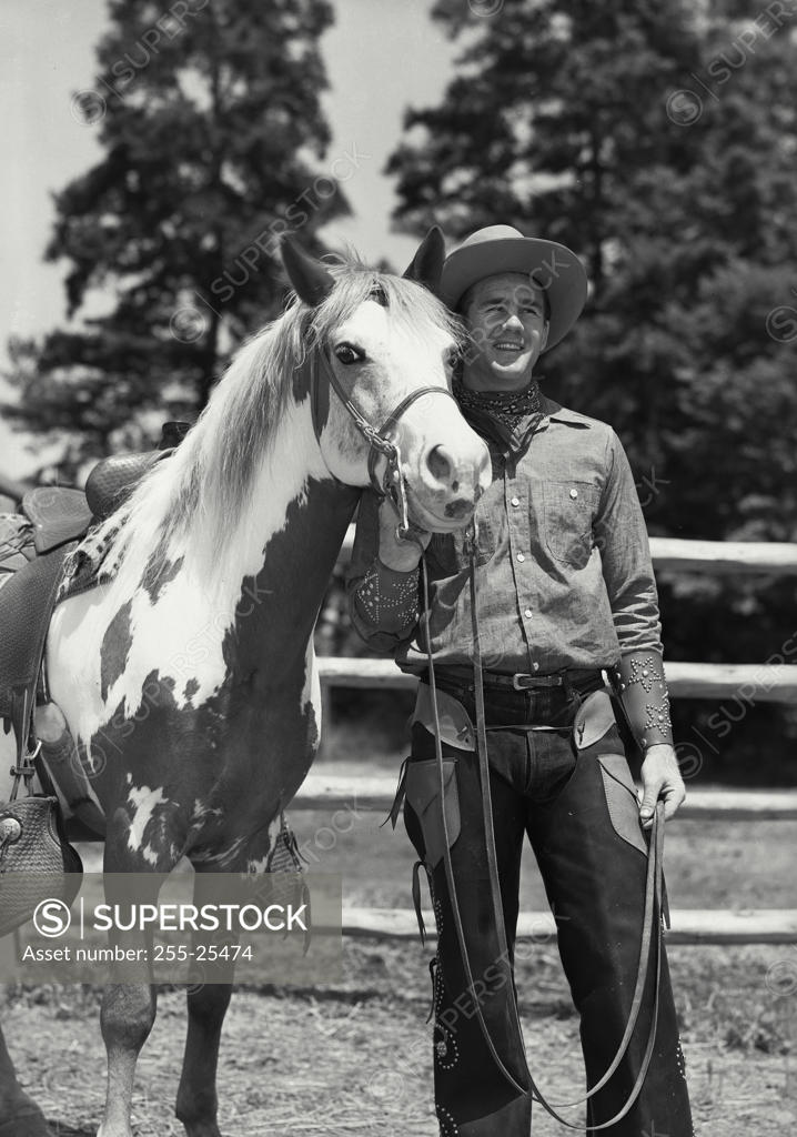 Stock Photo: 255-25474 Cowboy standing with his horse, smiling