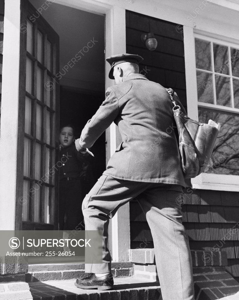 Stock Photo: 255-26054 Rear view of a postman giving mail to a boy