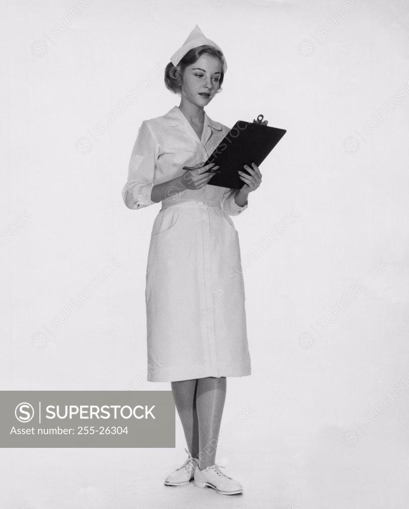 Stock Photo: 255-26304 Female nurse looking at a clipboard
