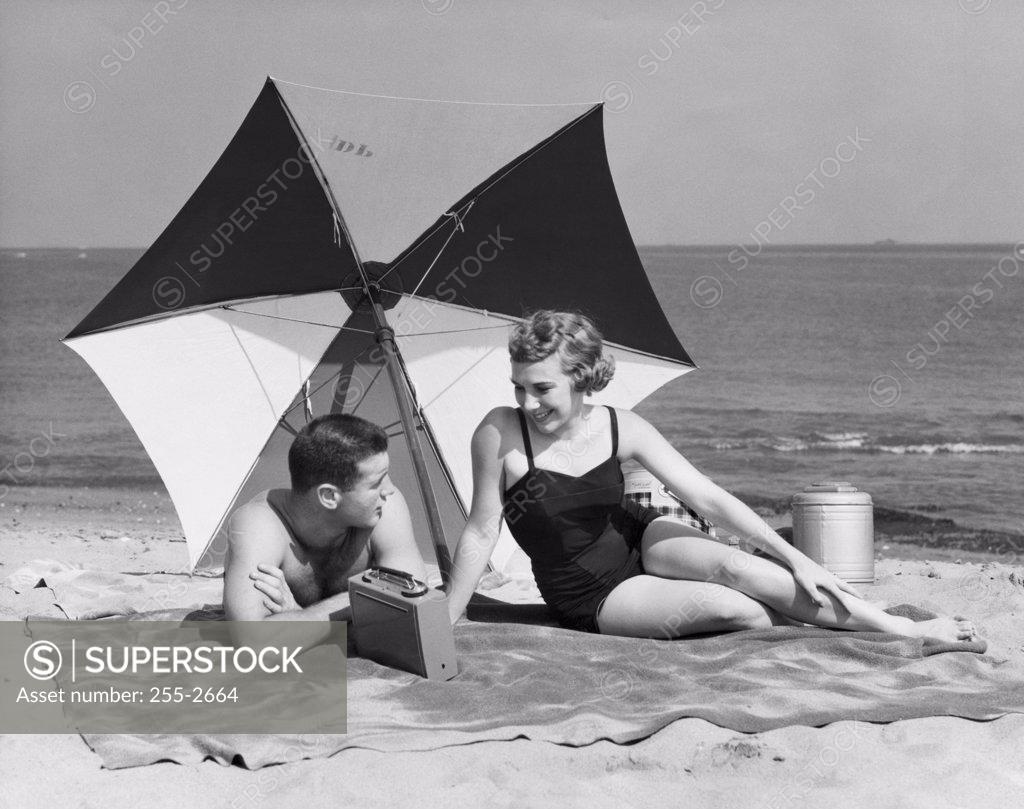 Stock Photo: 255-2664 Young couple listening to radio on beach