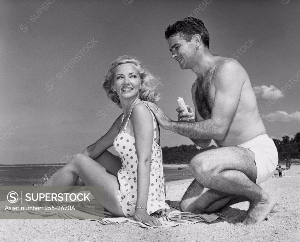 Stock Photo: 255-2670A Young man applying suntan lotion on a young woman's back at the beach