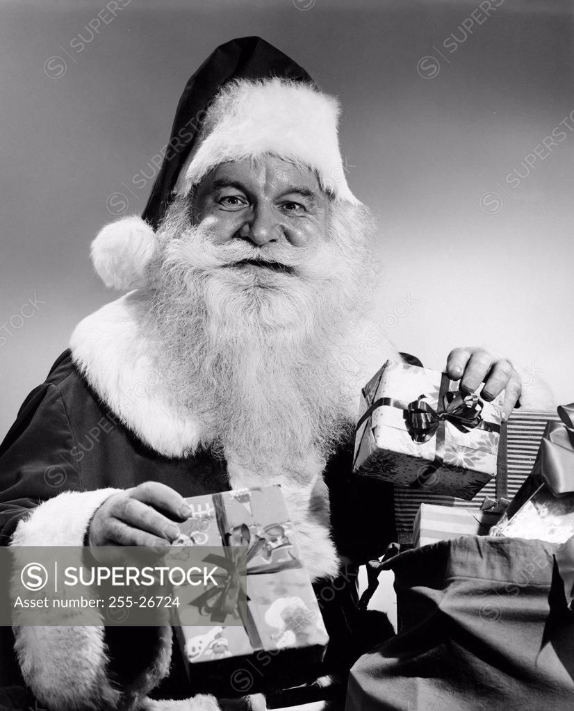 Stock Photo: 255-26724 Portrait of Santa Claus holding Christmas presents and smiling