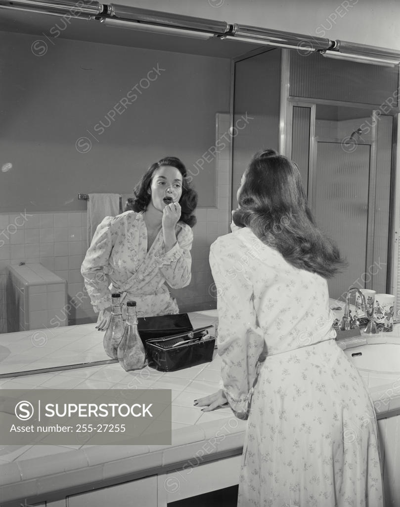Stock Photo: 255-27255 Reflection of a young woman applying a lipstick in a mirror