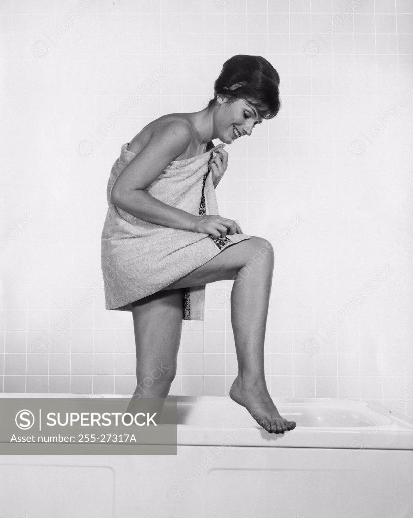 Stock Photo: 255-27317A Side profile of a young woman wrapped in a towel standing in a bathtub