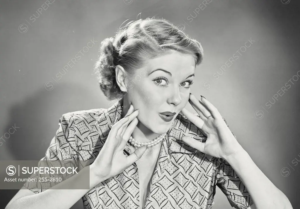 Vintage photograph. Woman with blonde hair holding up hands to face with pursed lips