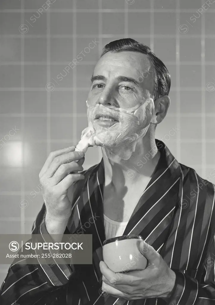 Vintage photograph. Man in robe applying shaving cream
