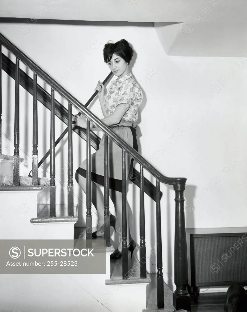Side profile of a young woman cleaning stairs with a mop