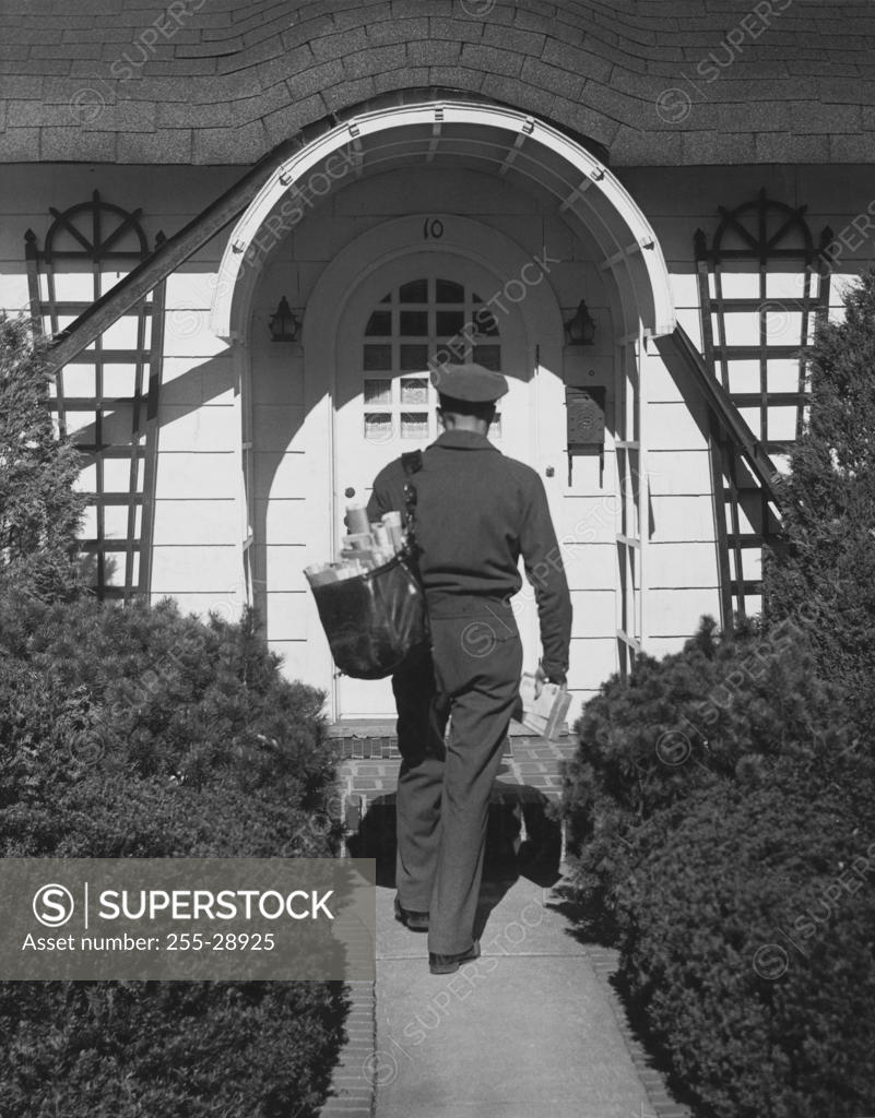 Stock Photo: 255-28925 Rear view of a postman delivering mail