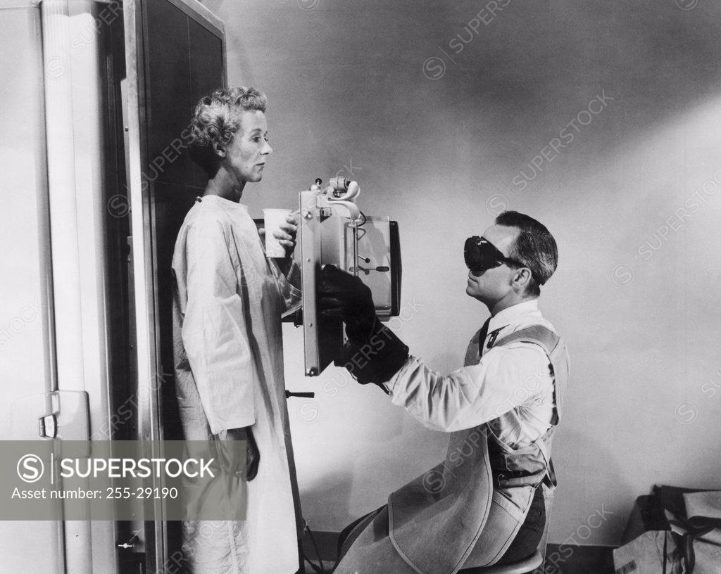 Stock Photo: 255-29190 Side profile of a male radiologist taking an x-ray of a female patient