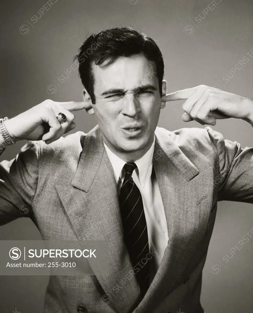 Close-up of a businessman closing his ears with his fingers