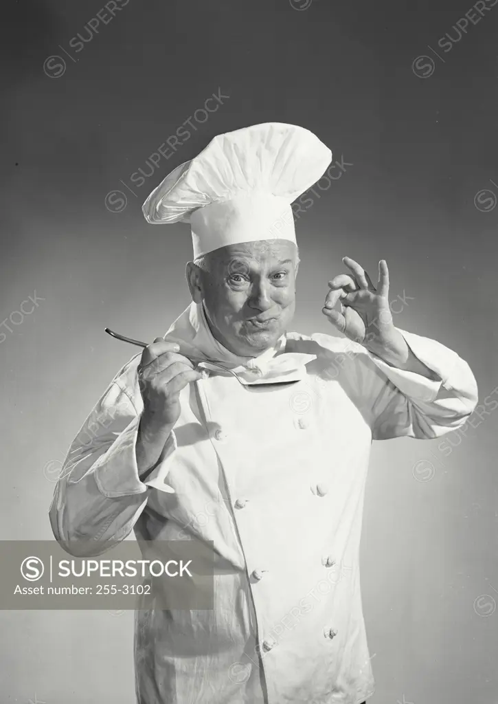 Man in chef uniform tasting spoon