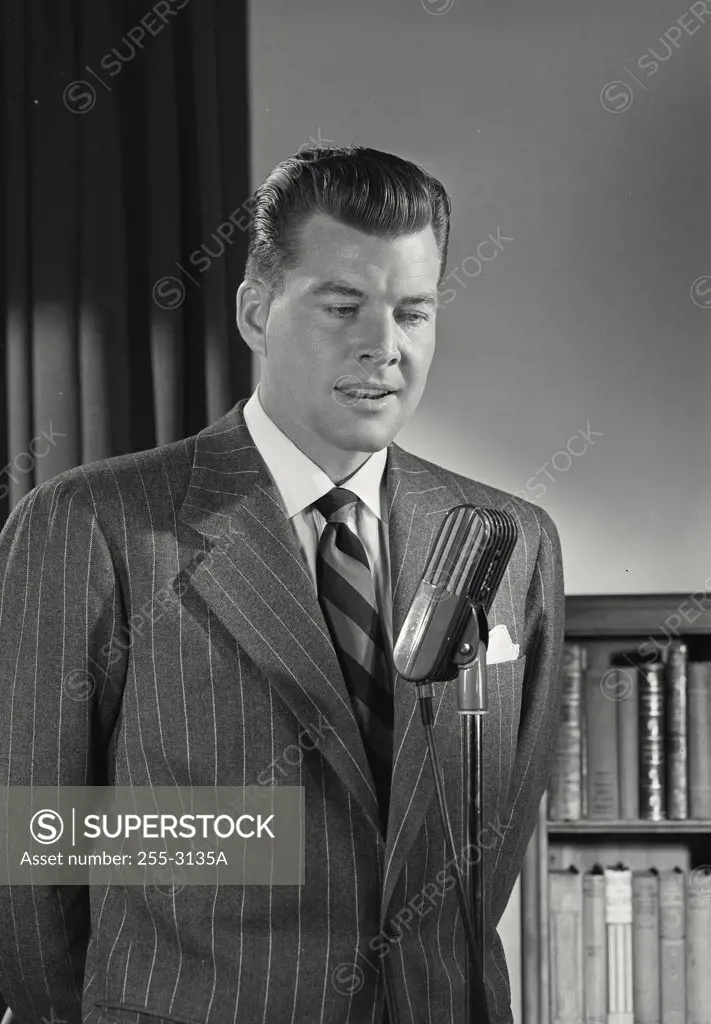 Man in pinstripe suit speaking into microphone