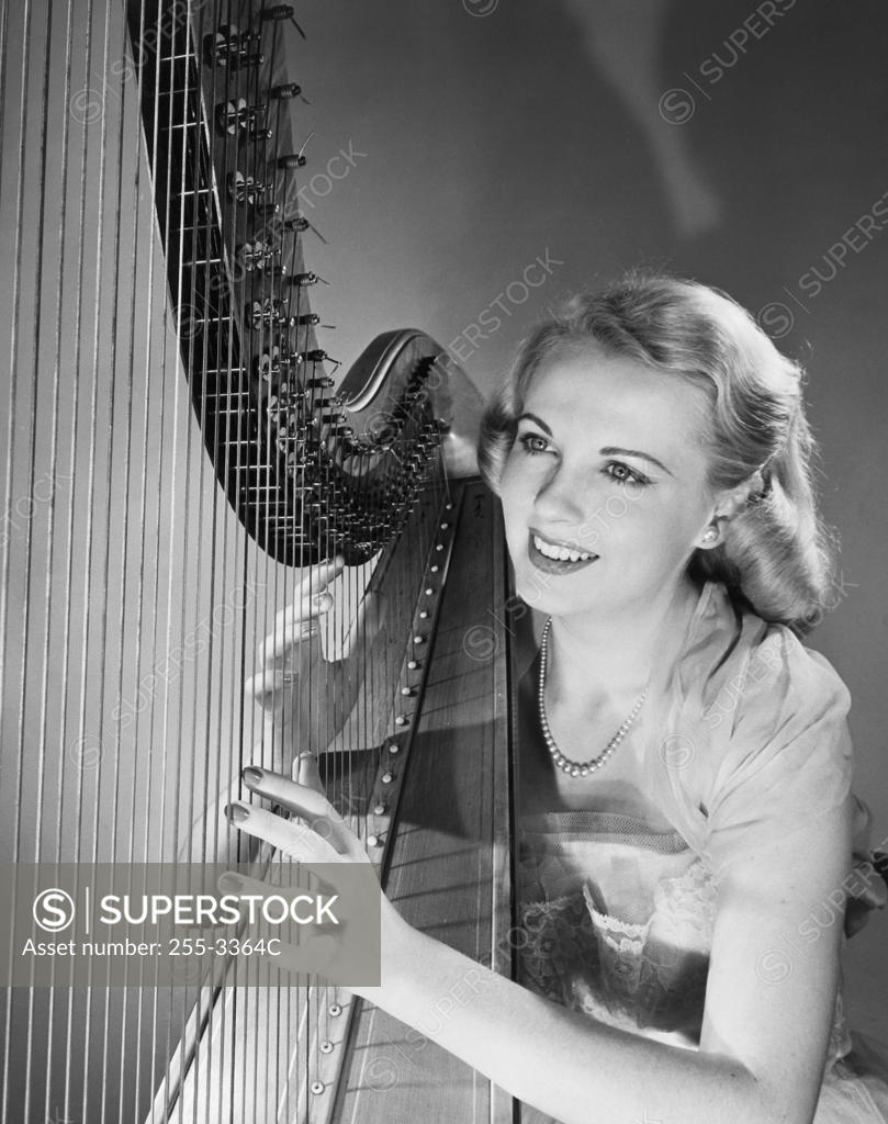 Stock Photo: 255-3364C Young woman playing a harp and smiling