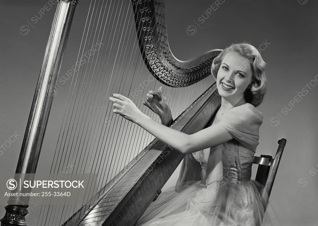 Stock Photo: 255-3364D Young woman playing a harp and smiling