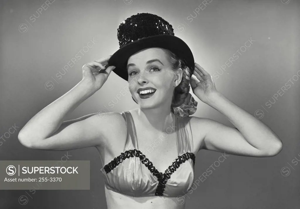 Vintage photograph. Young woman smiling in bra and top hat