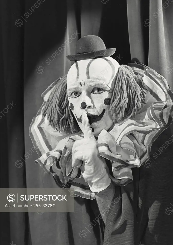 Vintage photograph. Portrait of clown wearing silly hat with finger up to lips