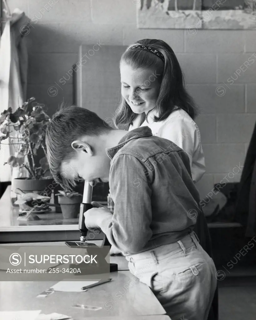 Side profile of a boy looking through a microscope