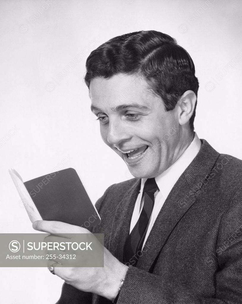 Stock Photo: 255-34312 Close-up of a young man holding a bankbook and laughing