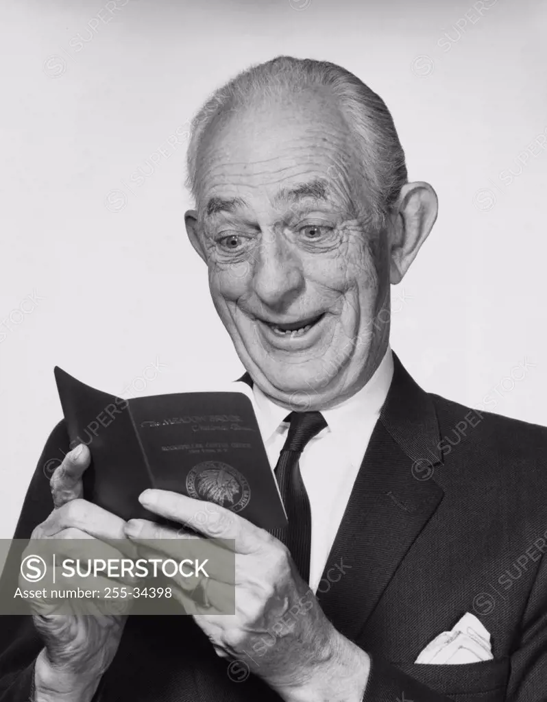 Close-up of a senior man looking at a bankbook and smiling