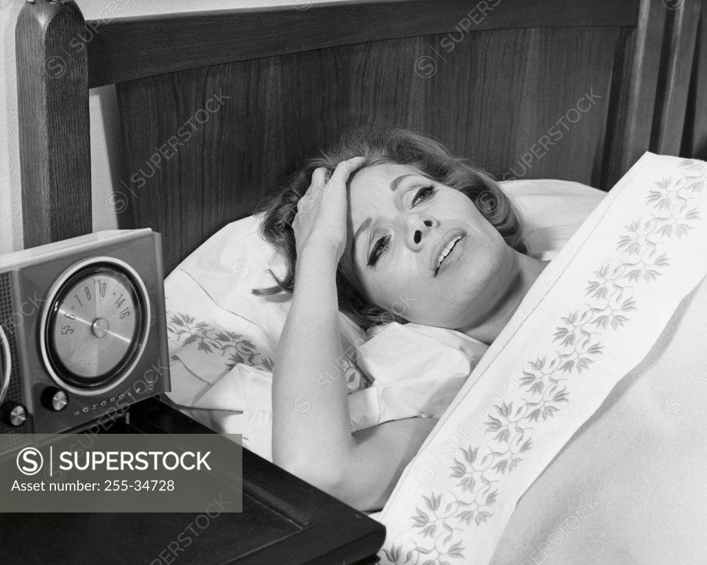 Stock Photo: 255-34728 High angle view of a mid adult woman lying in bed suffering from a headache