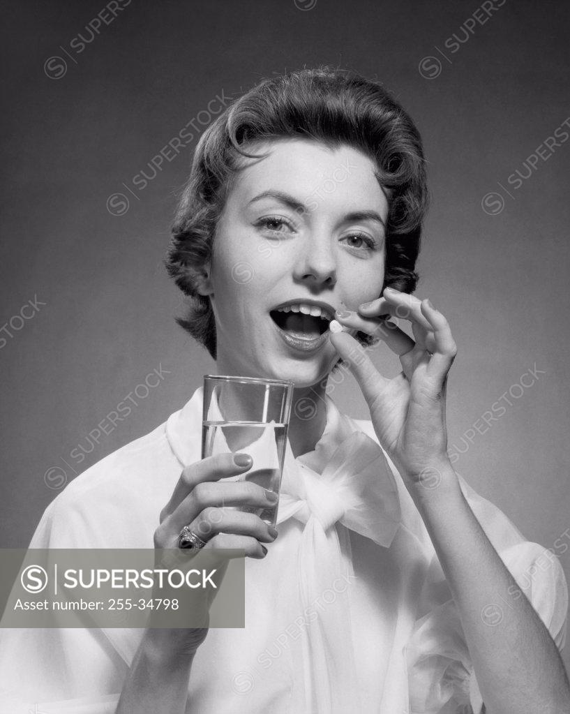 Stock Photo: 255-34798 Close-up of a young woman taking a pill