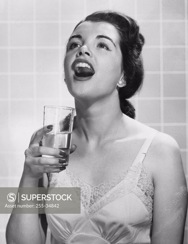 Stock Photo: 255-34842 Close-up of a young woman holding a glass of water and gargling