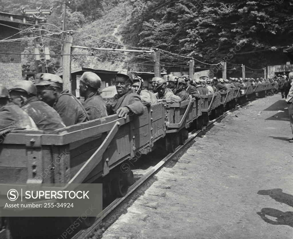 Stock Photo: 255-34924 Group of miners going into a mine on carts